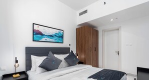 A modern bedroom with a bed, nightstand, and a painting on the wall. - Executive 1 BR in Oasis - 2 (Abu Dhabi)
