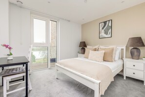 A bedroom with a bed, bedside tables, a desk, and a chair.