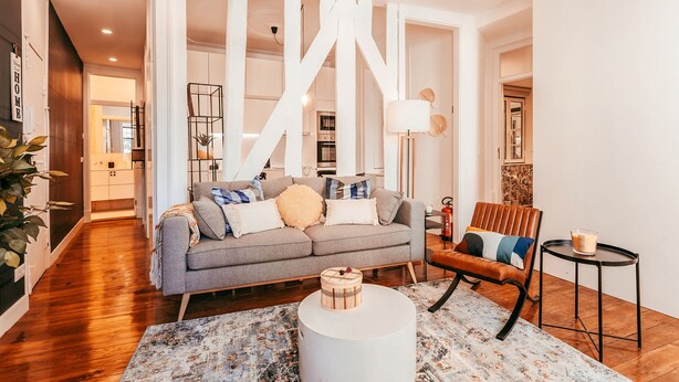 A modern living room with a grey sofa, a round coffee table, and a patterned rug.