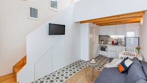 A modern apartment with a staircase, a living room with a sofa, a kitchen area, and a TV mounted on the wall. - Pestana Houses (Porto)
