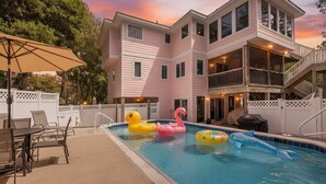 Un edificio de dos plantas con piscina, asientos al aire libre y una terraza.