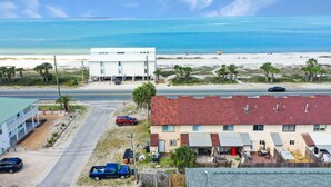 Un bâtiment situé sur la côte, avec un toit rouge, jouxtant une plage aux eaux bleues et cristallines.