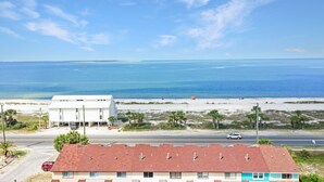 Un bâtiment situé sur la côte, avec un toit rouge, jouxtant une plage et l’océan.