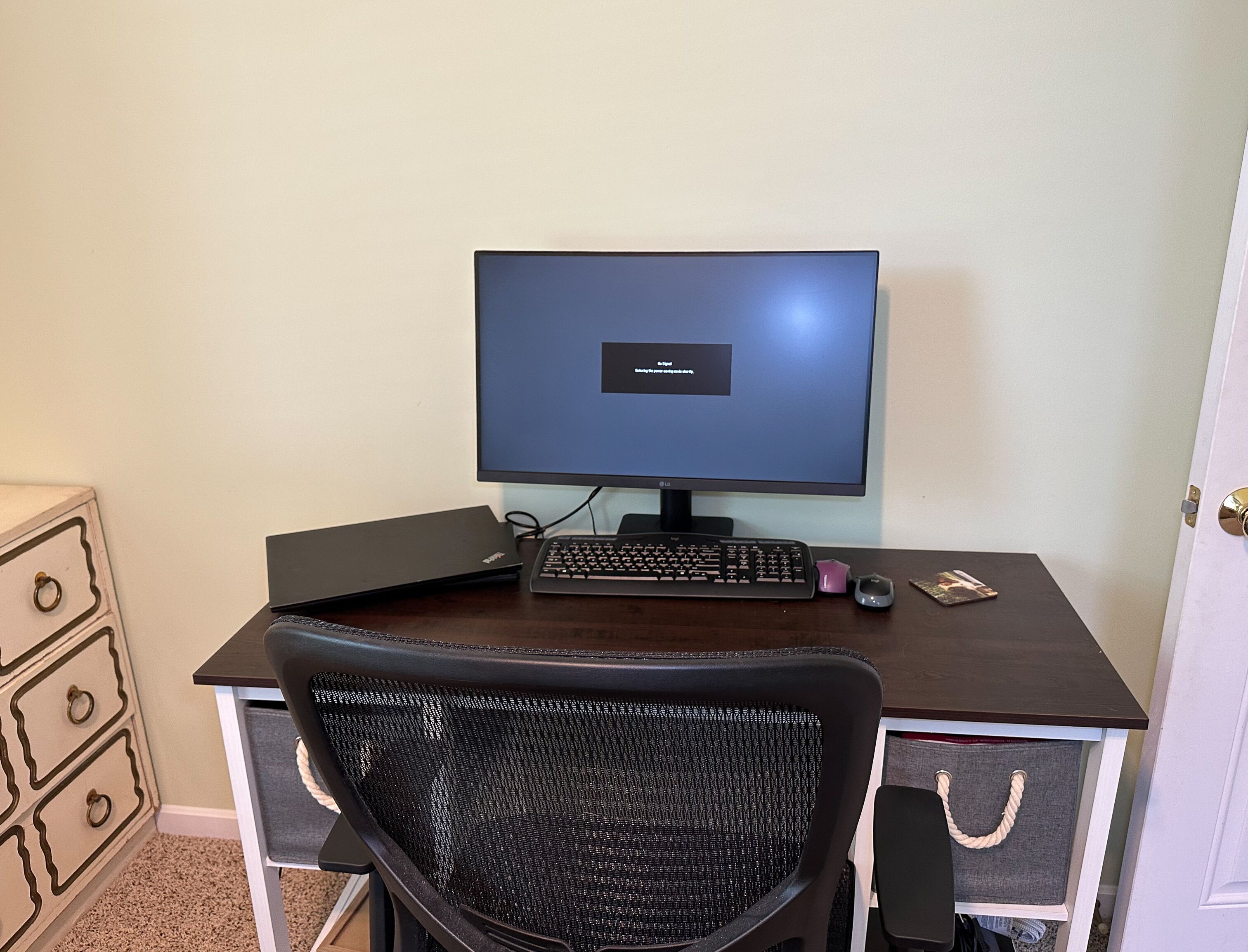 A computer desk with a monitor, keyboard, and chair.
