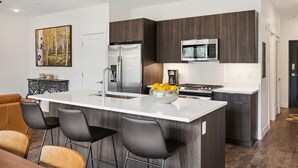 A modern kitchen with a central island, stainless steel appliances, and dark wood cabinetry. - River West 924 - Silverthorne Condo with River Views. (Silverthorne)