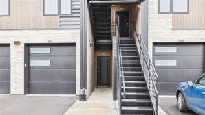 A building with a staircase leading to a door marked 913, a blue car parked nearby, and two garage doors labeled 161 and 163. - River West 924 - Silverthorne Condo with River Views. (Silverthorne)