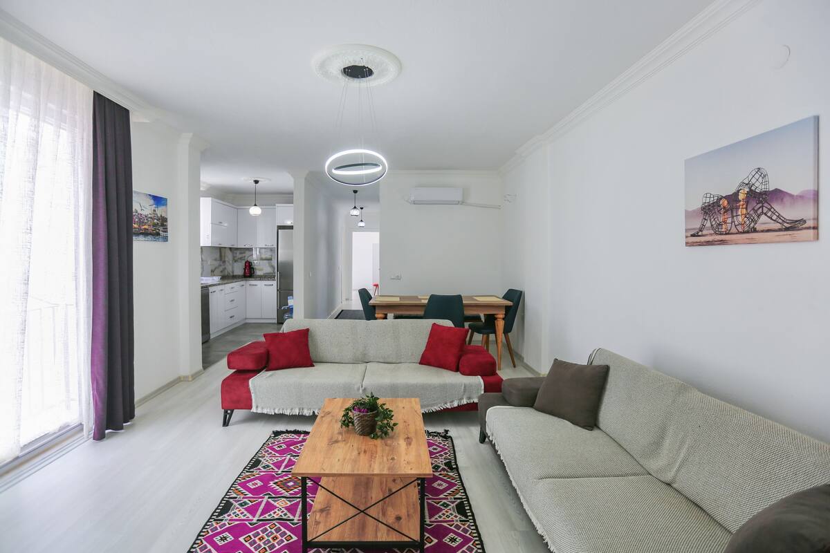 Un salon moderne avec un canapé, une table basse et, au fond, un coin repas.