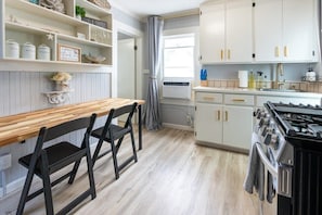 Una cocina con armarios blancos, una mesa de madera y una estufa negra.