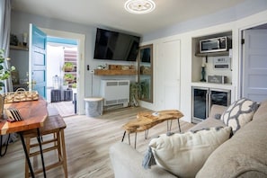 Una sala de estar moderna con una mesa de centro de madera, un sofá color beige y un televisor montado en la pared.