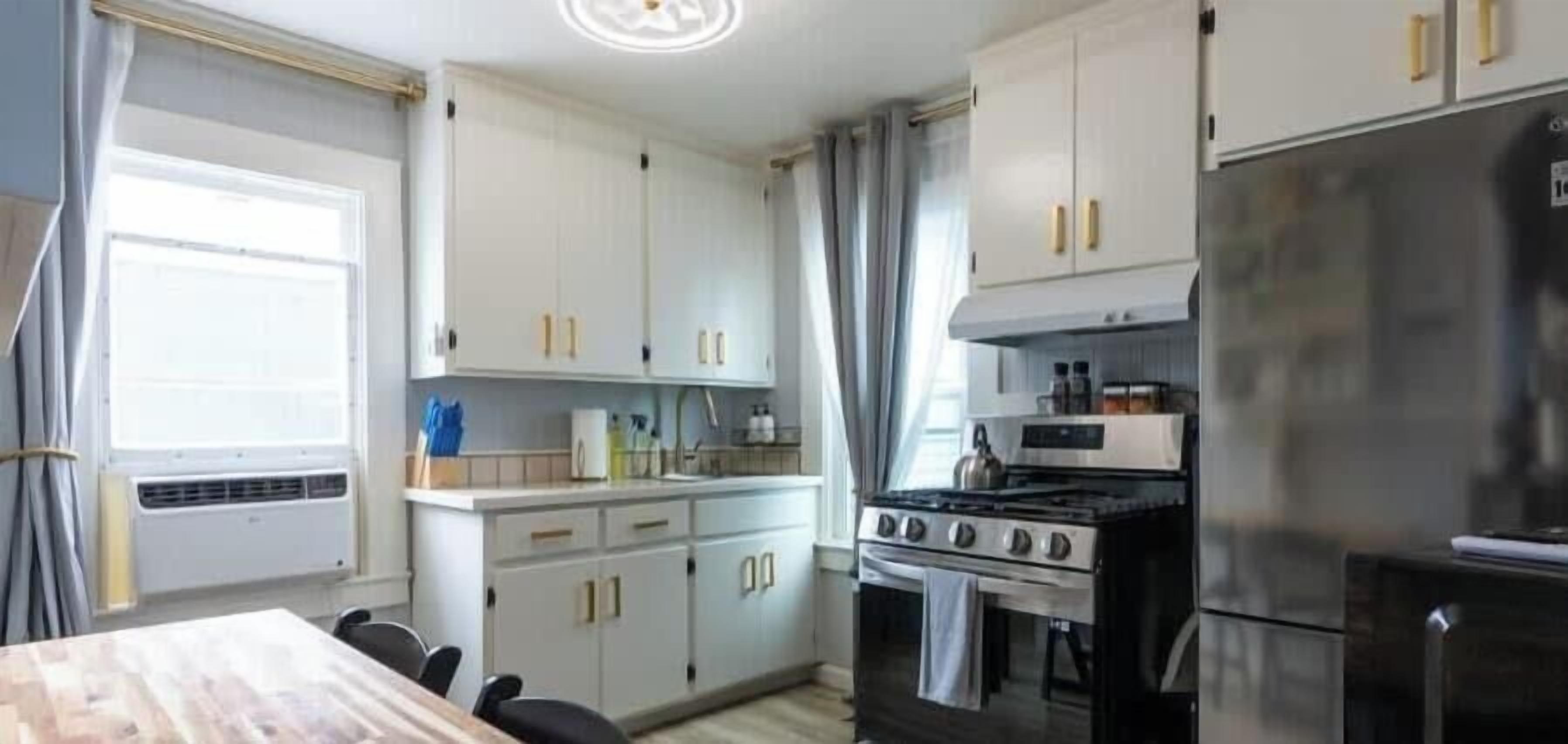 A kitchen with white cabinets, a stove, and a refrigerator.