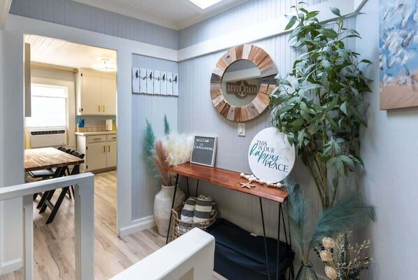 A modern interior with a wooden dining table, a round mirror, and a welcome sign.