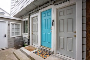 A house with a blue front door, a white garage door, and a wooden barrel outside.