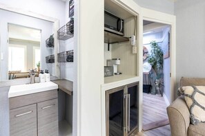Una cuina moderna amb microones integrat, taulell blanc i nevera d'acer inoxidable.