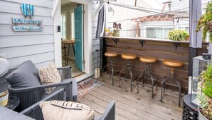 A covered outdoor seating area with wicker furniture and wooden stools. - Capitola Village Bungalow - 2 Blocks from the Sand (Capitola)