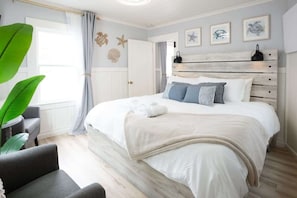Een slaapkamer met een groot bed, een houten hoofdeinde en uitzicht op zee door een raam.