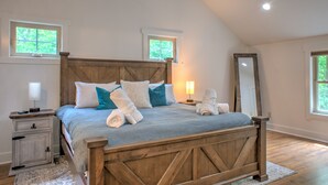 A bedroom with a wooden bed frame, a nightstand, a mirror, and two windows.