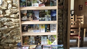 Una estantería llena de libros de viajes frente a una pared de piedra.
