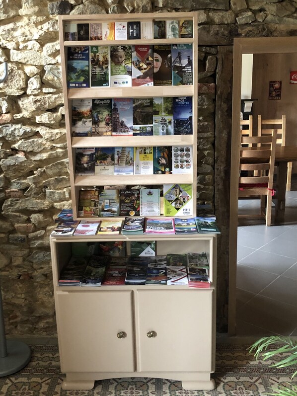 A bookcase with travel books against a stone wall. - Propriété de Campagne Rénovée Avec Barbecue, à Proximité Sentiers de Randonnées (Sivry-Rance)