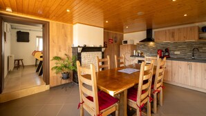 Una mesa de madera para comer con seis sillas, una planta en maceta y una zona de cocina con armarios y un microondas.