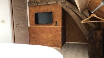 Une chambre avec un plafond en bois, un téléviseur fixé au mur et un lit.