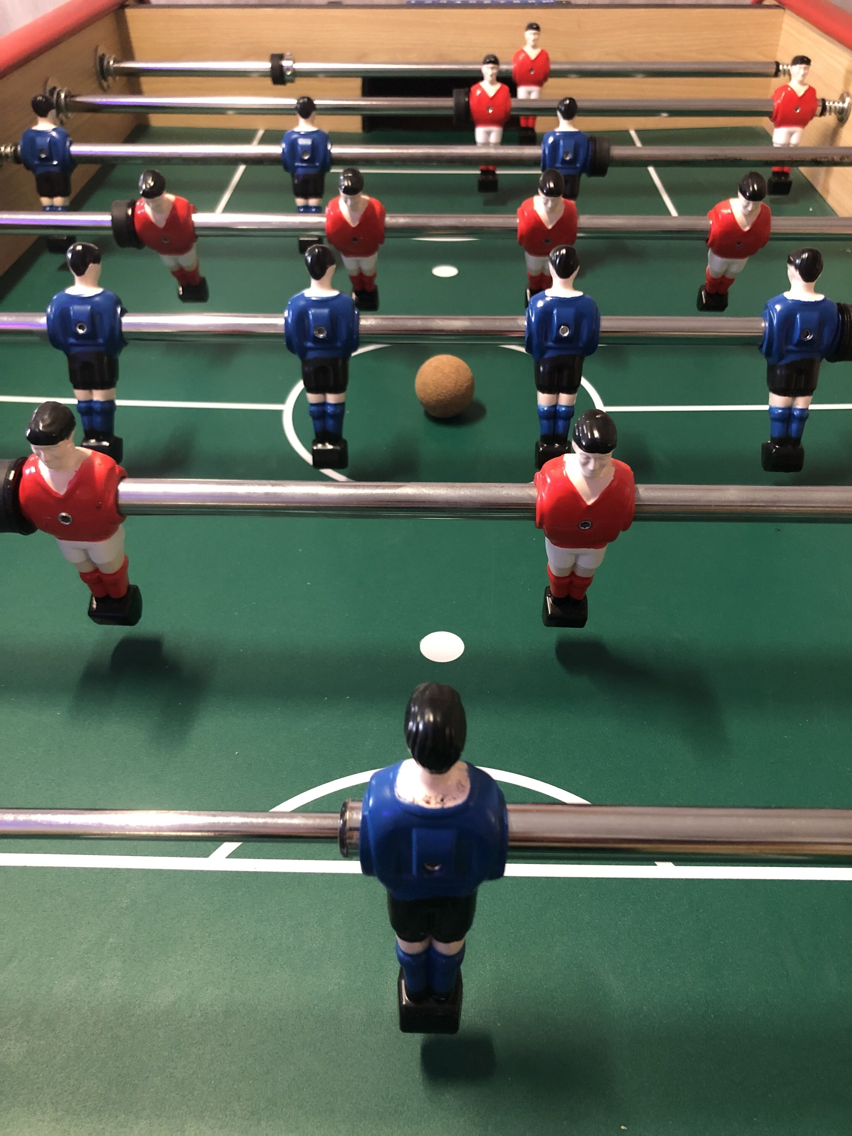 Un taula de futbolí amb jugadors uniformats de vermell i blau.