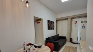A compact living space with a dining area, a black sofa, and a small kitchenette. - Neo Porto Family & Friends local accommodation. (União de Freguesias do Centro)