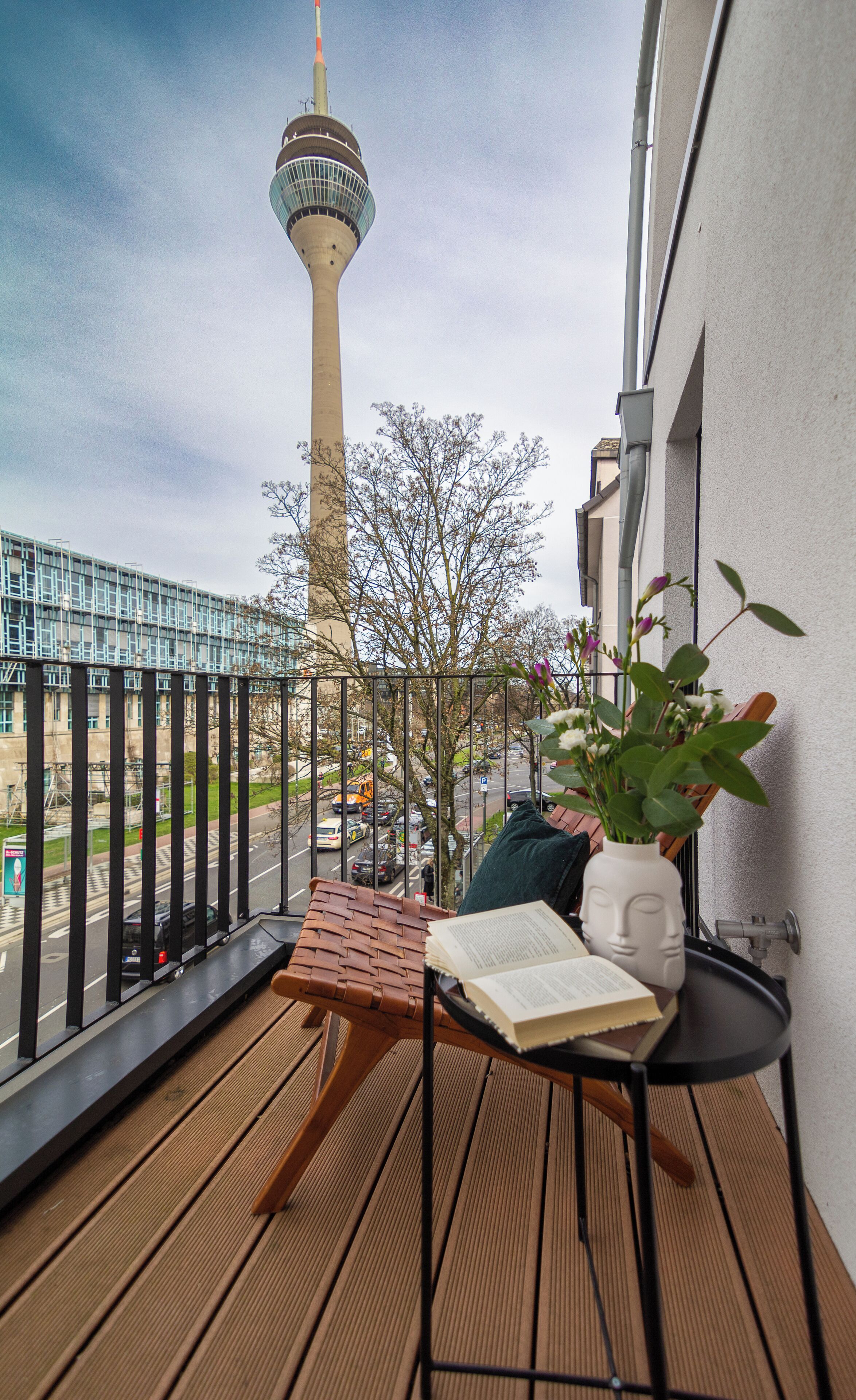 A balcony with a view of a tower, a potted plant, and a book on a small table.