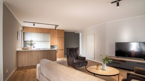 A modern living room with a sofa, armchairs, a coffee table, and a TV. - Sleep Inn Medienhafen Suites (Düsseldorf)