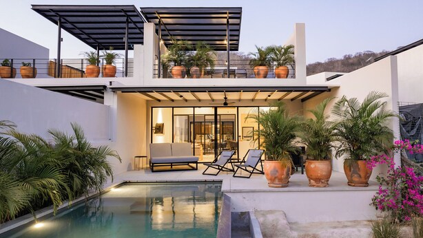A modern house with a swimming pool, outdoor seating, and potted plants. - Modern Villa Overlooking Lush National Park (Huatulco)