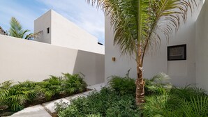 A modern building with a white exterior, surrounded by lush greenery and a palm tree. - Modern Villa Overlooking Lush National Park (Huatulco)