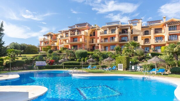 A hotel with a swimming pool, multiple balconies, and lush landscaping. - Premium apartment in Benahavis with balcony (BENAHAVIS)