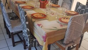 Ein Essbereich mit einem langen Tisch, gedeckt für sechs Personen, umgeben von stuhligen Sitzgelegenheiten mit Muster.