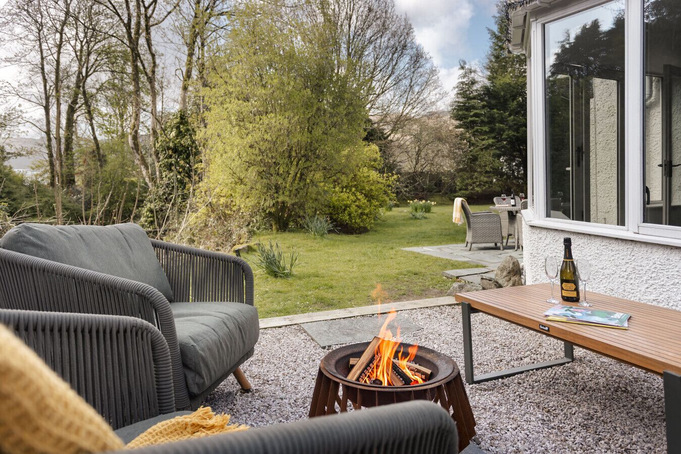 Une terrasse dotée d’un foyer extérieur, de mobilier de jardin et offrant une vue sur un jardin.