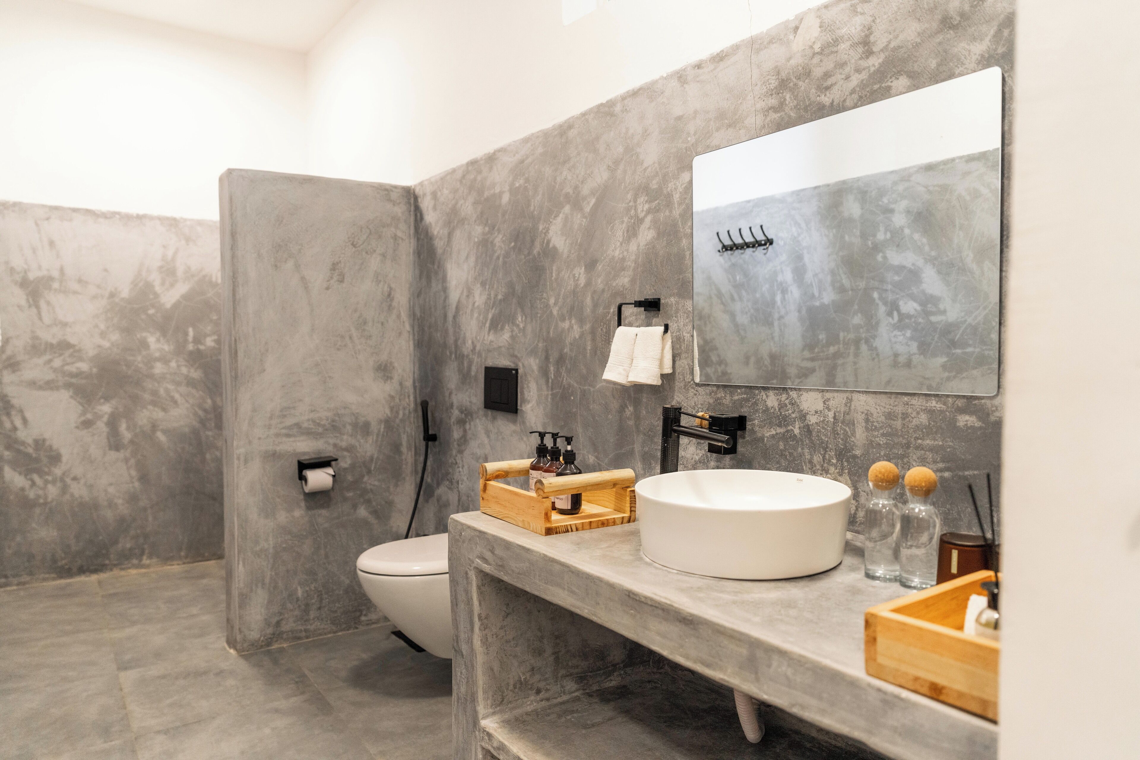 Un baño moderno con un espejo grande, un lavabo redondo y un inodoro.