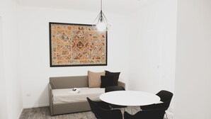 A modern room with a sofa, a round table, and black chairs. There is a large framed artwork on the wall above the sofa. - Located in the city center convenient to walk and drive to. (Matera)