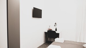 A modern hotel room with a bed, a desk, and a flat-screen TV mounted on the wall. - Located in the city center convenient to walk and drive to. (Matera)