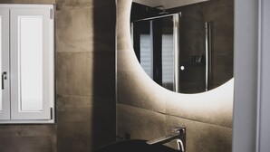 A modern bathroom with a curved mirror, a sink, and a shower. - Located in the city center convenient to walk and drive to. (Matera)