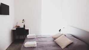 A minimalist bedroom with a bed, a desk, and a chair. - Located in the city center convenient to walk and drive to. (Matera)