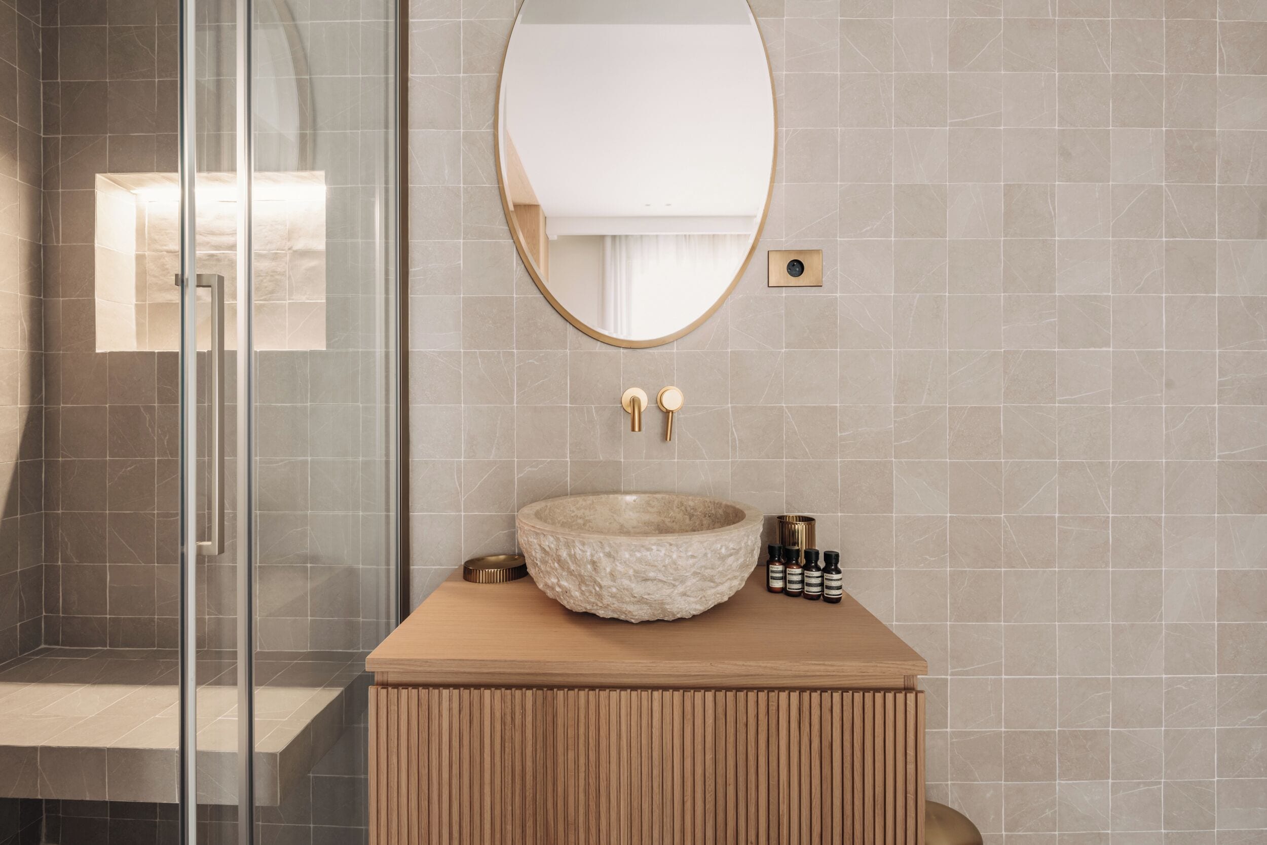 A bathroom with a stone sink, a glass shower enclosure, and a wooden vanity.