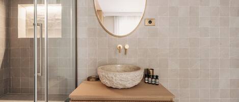 A bathroom with a stone sink, a glass shower enclosure, and a wooden vanity.