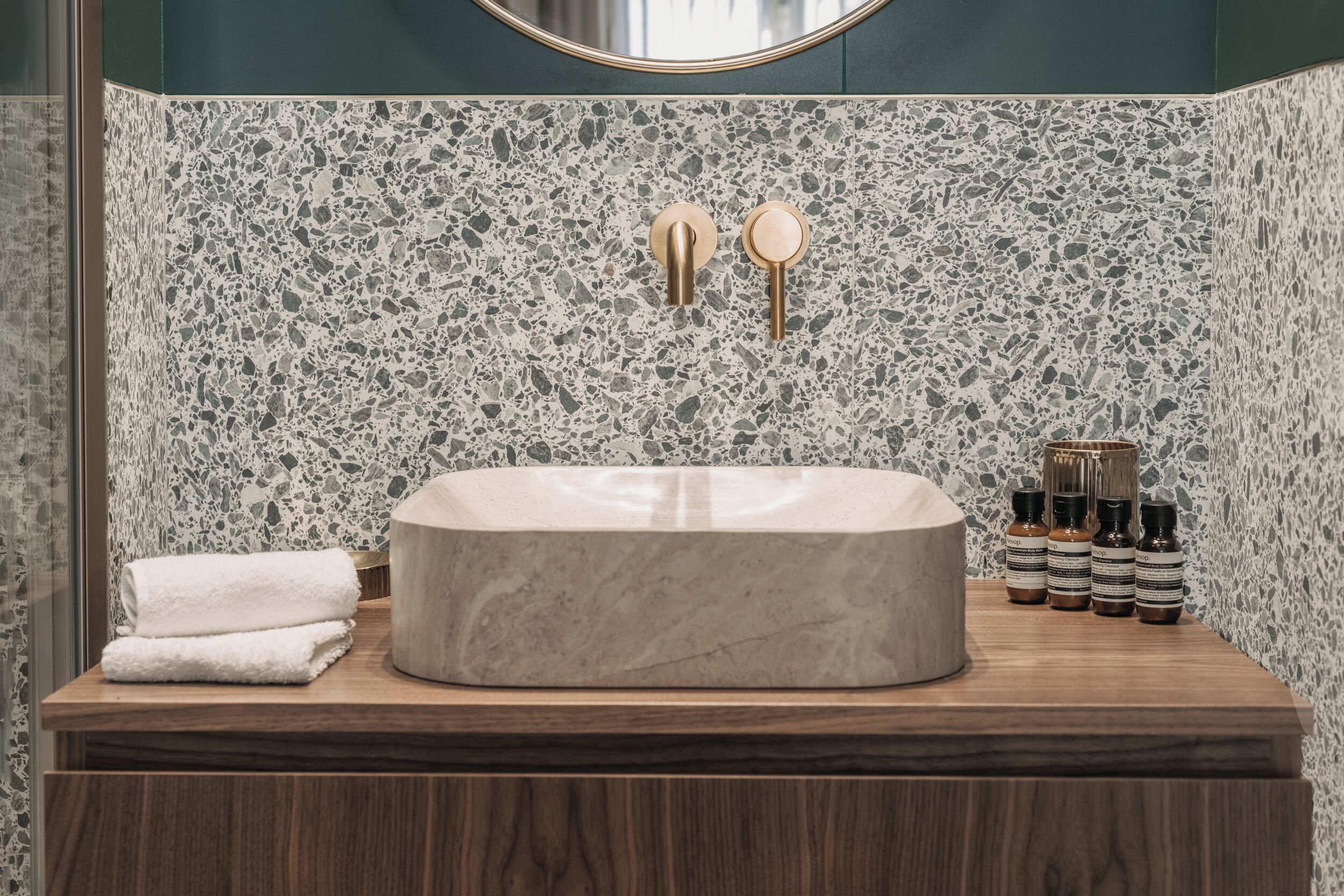 A bathroom with a freestanding marble sink, wooden vanity, and a speckled backsplash.