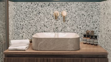 Une salle de bain dotée d’un lavabo en marbre indépendant, d’un meuble-lavabo en bois et d’un pare-éclaboussures à motifs.