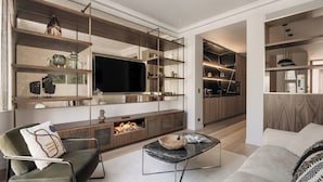 A modern living room with a flat-screen TV, built-in shelves, a fireplace, and a cozy seating area.