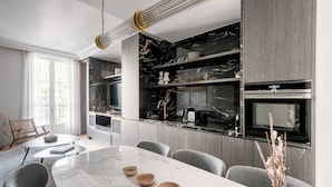 A modern kitchen with marble countertops, built-in appliances, and a dining area with a marble table and chairs.