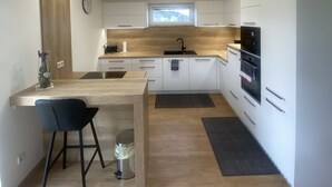 Eine moderne Küche mit weißen Schränken, einer Holzarbeitsplatte, einer Spüle und einem Backofen.