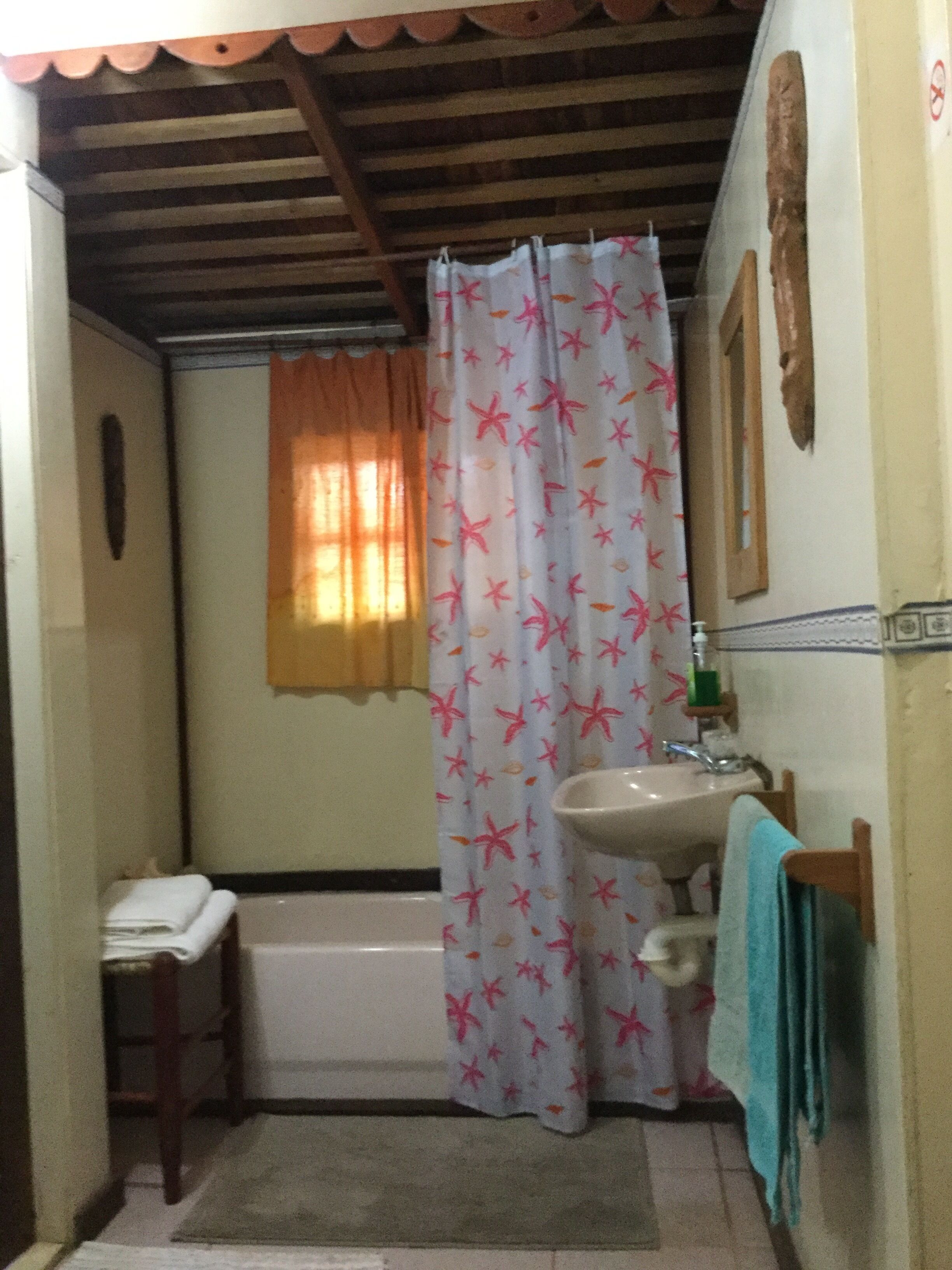 A small bathroom with a shower curtain, a sink, and a bathtub.