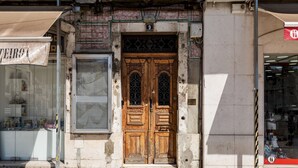 A building with a large wooden double door, a shop with a sign reading "TEIRO", and a visible number "9" above the door. - Master Deco Gem in Baixa (Lisboa)
