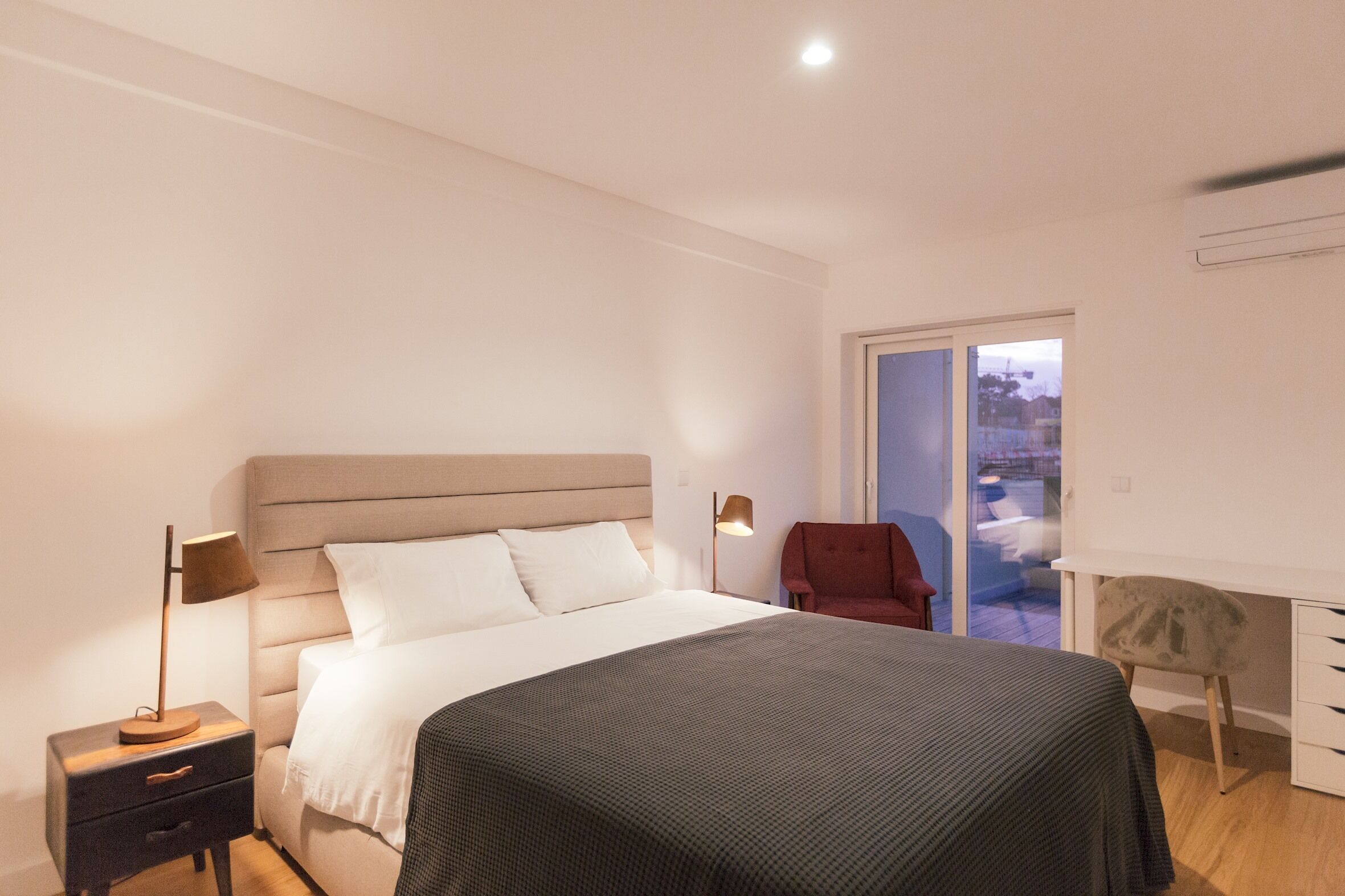 Ein modernes Schlafzimmer mit Bett, Nachttischen, Schreibtisch und Stuhl.