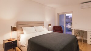 A modern bedroom with a bed, bedside tables, a desk, and a chair. - Master Deco Gem in Cascais (Cascais)