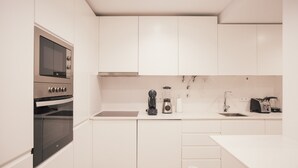 A modern kitchen with white cabinetry, a built-in oven, a coffee maker, and a toaster. - Master Deco Gem in Cascais (Cascais)
